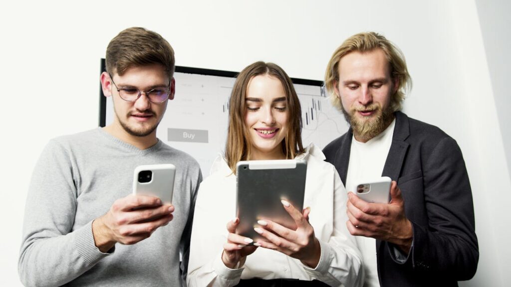 Three professionals using digital devices for financial analysis in an office setting.